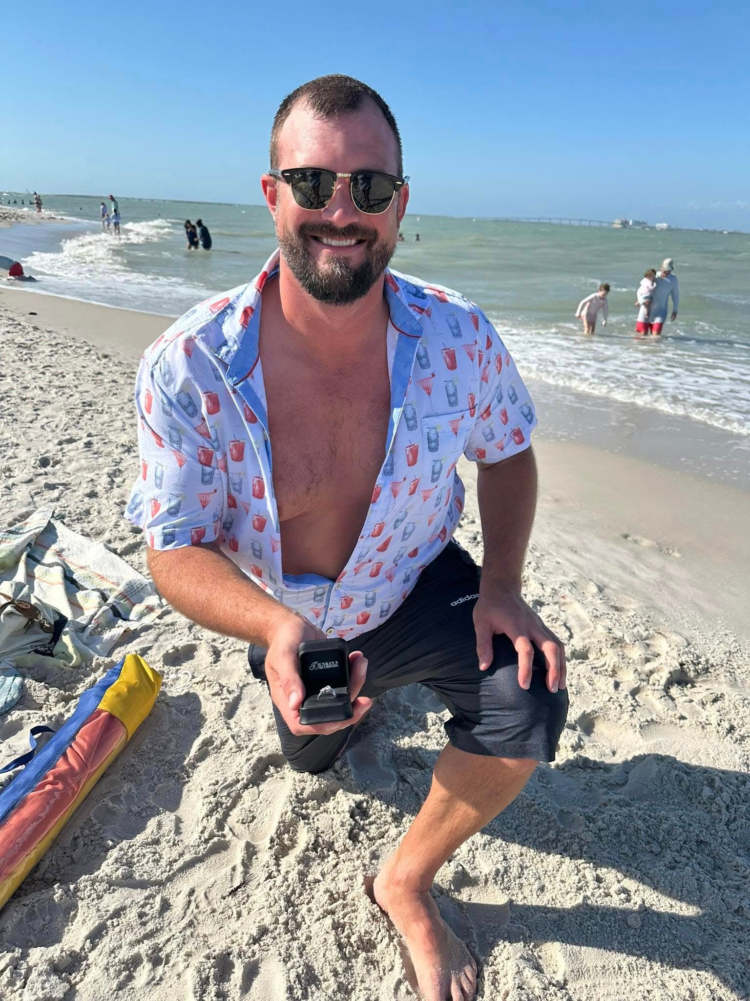 Alexander on one knee on the beach, holding the ring